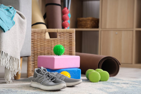 Sneakers, wicker basket and different sports equipment on floor in living room, closeupの写真素材
