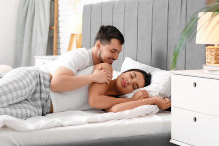 Young man with his sleeping wife in bedroomの写真素材