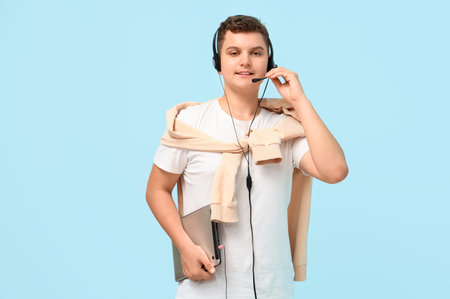 Teenage boy with tablet computer and headset working on blue background