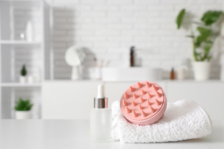 Hair scalp massager with towel and serum on shelf in bathroom, closeupの写真素材