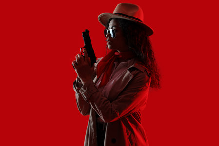 Female African-American spy with gun on red backgroundの写真素材