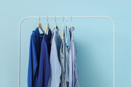 Rack with female clothes near blue wall