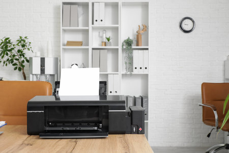 Modern printer on wooden table in stylish officeの写真素材