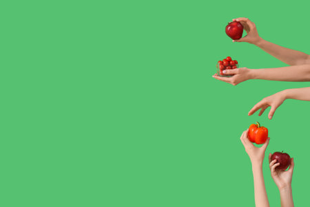 Hands with fresh apples, bell pepper and tomatoes on green backgroundの写真素材