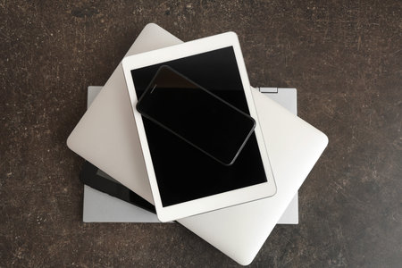 Stack of modern gadgets on dark background