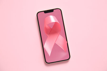 Modern mobile phone and pink ribbon on color background. Breast cancer awareness conceptの写真素材