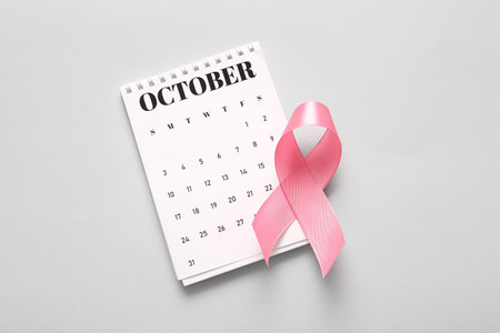 Pink ribbon and calendar on gray background. Breast cancer awareness conceptの写真素材