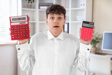 Male accountant holding different calculators in officeの写真素材