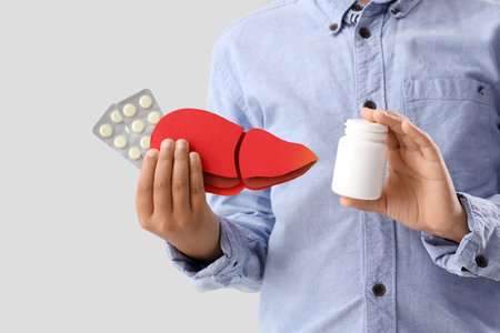 Little boy with paper liver and pills on light background, closeupの写真素材