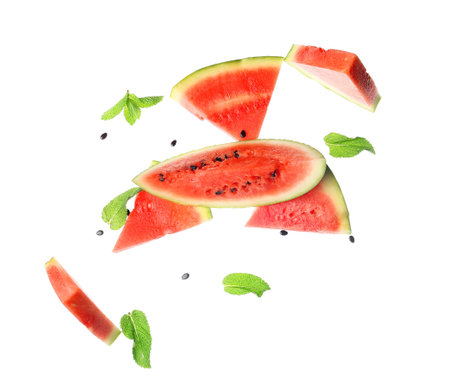 Flying pieces of fresh watermelon with mint and seeds on white backgroundの写真素材