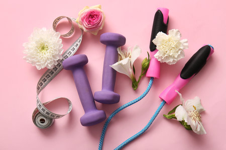Composition with beautiful flowers and sports equipment on pink backgroundの写真素材