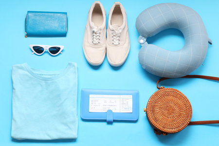 Travel pillow, wallet, ticket and beach accessories on blue backgroundの写真素材
