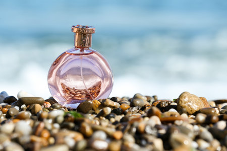 Bottle of elegant perfume on pebble beach near oceanの写真素材