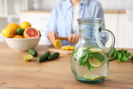 Young woman cutting lemon for preparing infused water in kitchenの写真素材