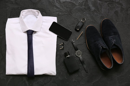Set of male accessories with shirt, mobile phone and shoes on black background. Top view