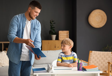 Young father helping his little son with homework at homeの写真素材