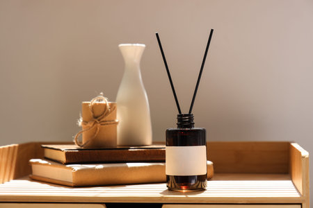 Bedside table with aroma diffuser, books, vase and candle, closeup