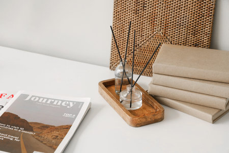 Wooden tray with aroma diffusers and books on table in room