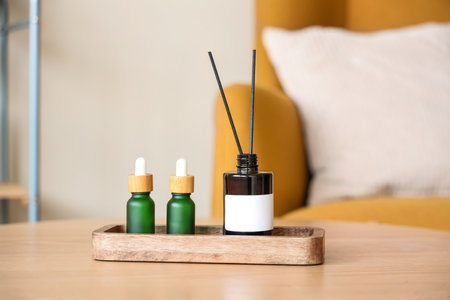 Wooden tray with aroma diffuser and bottles of essential oil on table in roomの写真素材