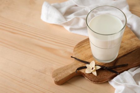 Glass of fresh vanilla milk with sticks and flowers on wooden backgroundの写真素材