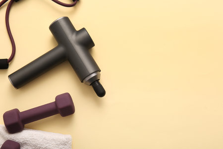 Percussive massager, dumbbells and expander on color backgroundの写真素材