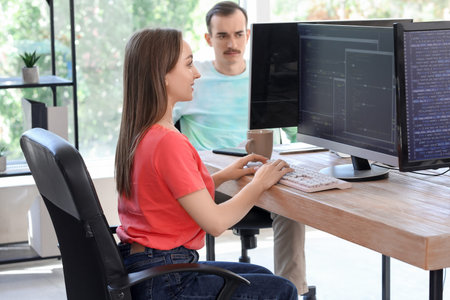 Young female programmer working with computer in office