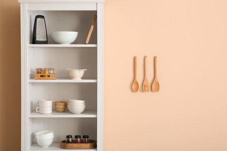 Shelving unit with kitchen utensils near beige wallの写真素材