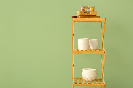 Shelving unit with crockery near green wallの写真素材