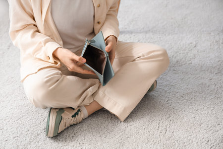 Bankrupt young woman with empty wallet sitting at home, closeup
