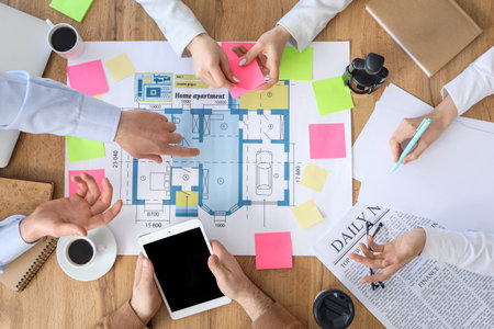 Business people working on house plan at table in office, top view