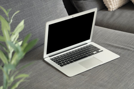 Modern laptop on black sofa in living room, closeupの写真素材