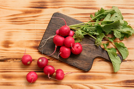 Board with fresh radishes on wooden background