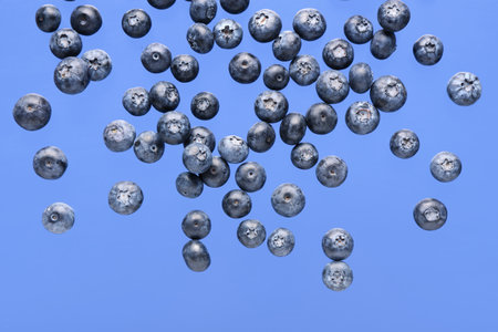 Flying sweet fresh blueberries on blue backgroundの写真素材