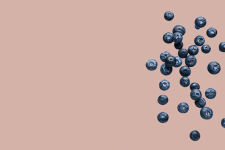 Flying fresh blueberries on beige backgroundの写真素材