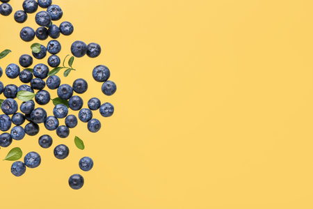 Flying sweet fresh blueberries and leaves on yellow backgroundの写真素材