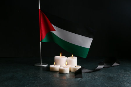 Flag of Palestine with burning candles and black ribbon on dark backgroundの写真素材