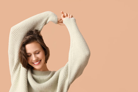 Happy young woman in stylish gray sweater on brown backgroundの写真素材
