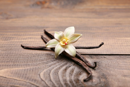 Beautiful vanilla flower and sticks on wooden background