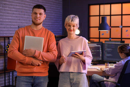 Young programmers with gadgets in office at night
