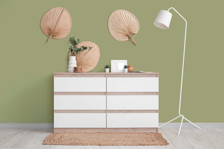 Interior of living room with commode, artificial plants and lamp