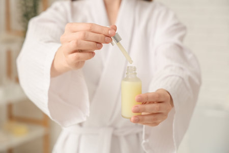 Young woman with bottle of cosmetic oil and pipette, closeupの写真素材
