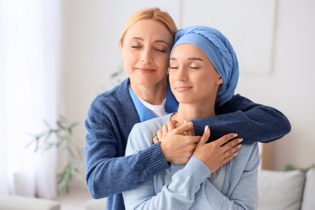 Young woman after chemotherapy with nurse hugging at homeの写真素材