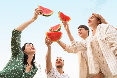 Young friends with slices of watermelon on picnic in parkの写真素材