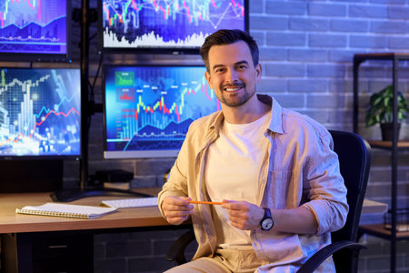 Male trader smiling in office at night
