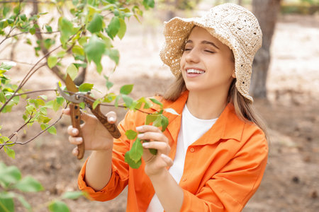 Young woman with secateurs cutting branch in garden, closeupの写真素材