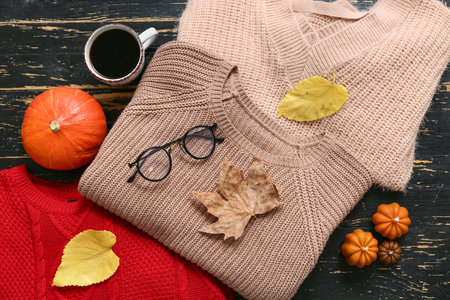 Composition with cup of coffee, warm sweaters and autumn decor on dark wooden backgroundの写真素材