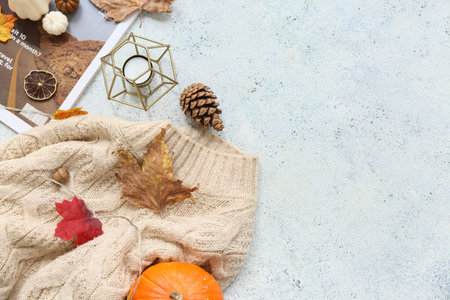 Composition with warm sweater, magazine and beautiful autumn decor on light background