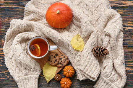 Composition with cup of tea, warm sweater, candles and autumn decor on dark wooden backgroundの写真素材
