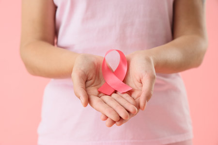 Young woman with pink ribbon on color background, closeup. Breast cancer awareness conceptの写真素材