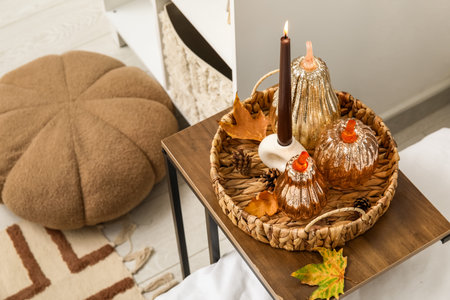 Decorative pumpkins with burning candle and autumn leaves on table in bedroom, closeupの写真素材